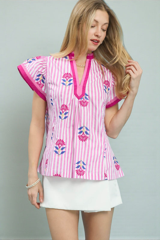 Woman wearing a pink and white patterned top with a plain background