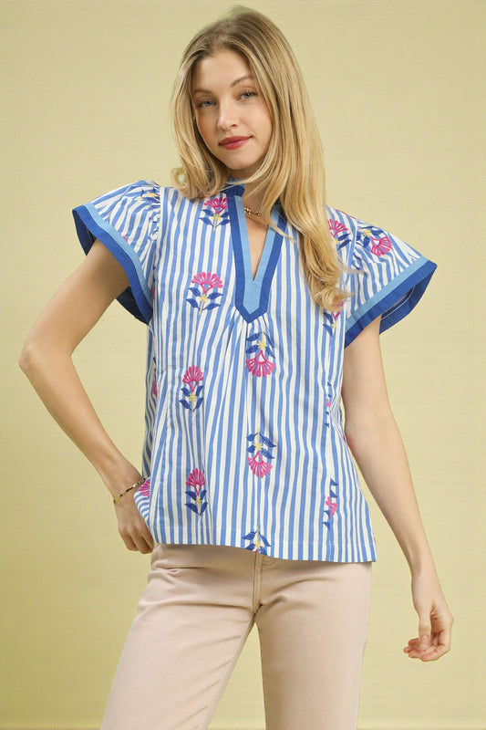 Woman wearing a blue and white striped blouse with floral patterns on a beige background
