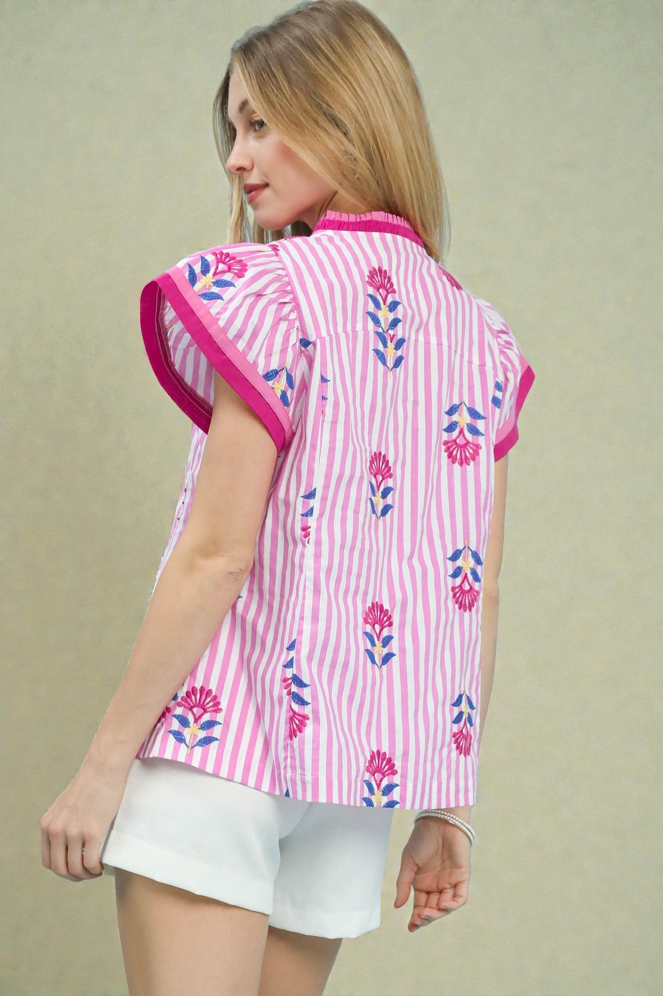 Woman wearing a pink and white striped shirt with floral patterns on a beige background