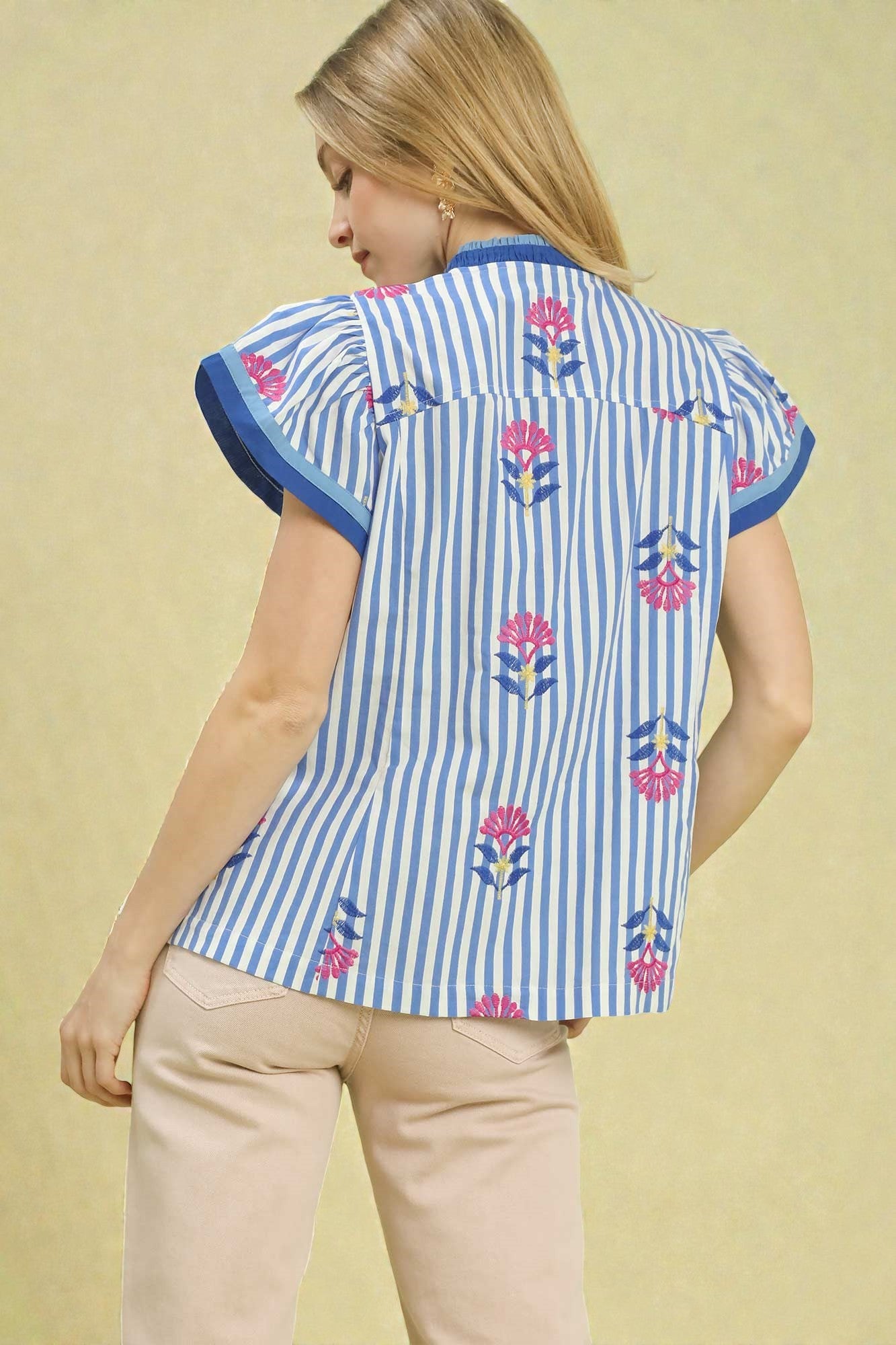 Woman wearing a blue and white striped shirt with floral patterns on a beige background