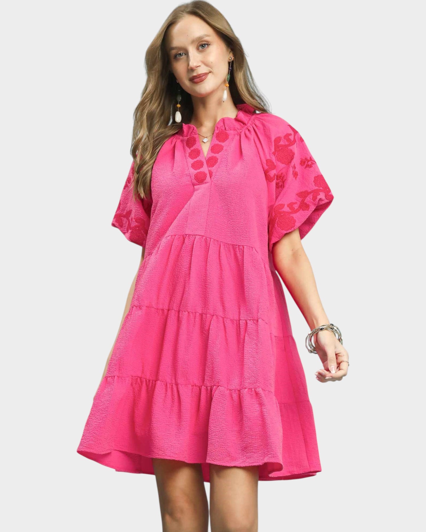 Woman wearing a pink dress with floral patterns on a white background