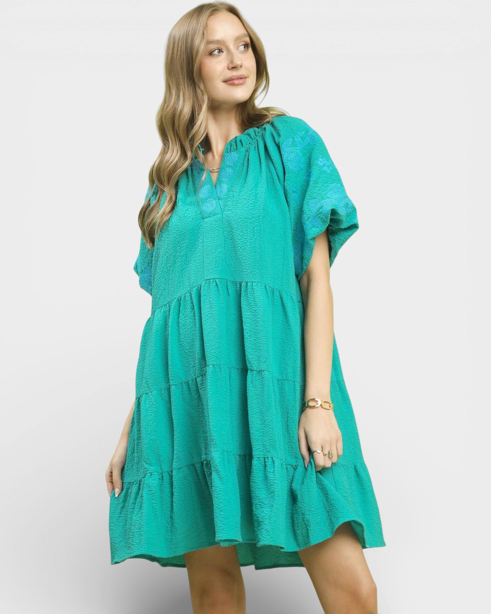 Woman wearing a teal dress on a white background