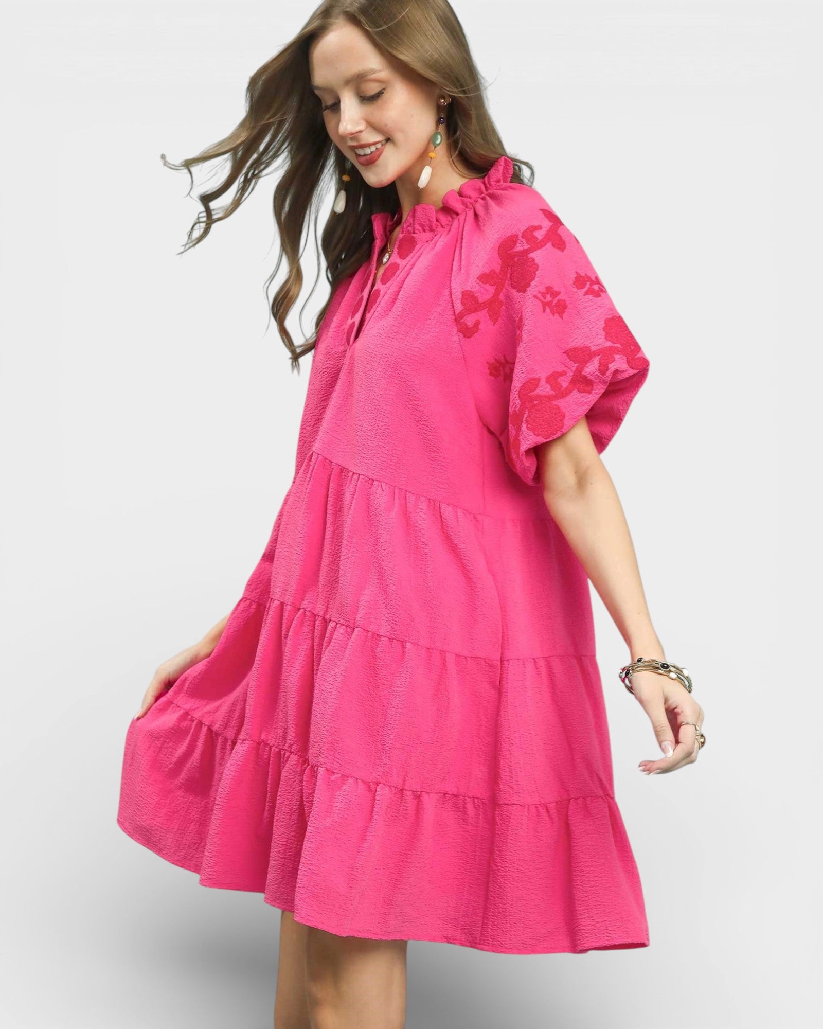 Woman wearing a pink dress with floral patterns on a white background