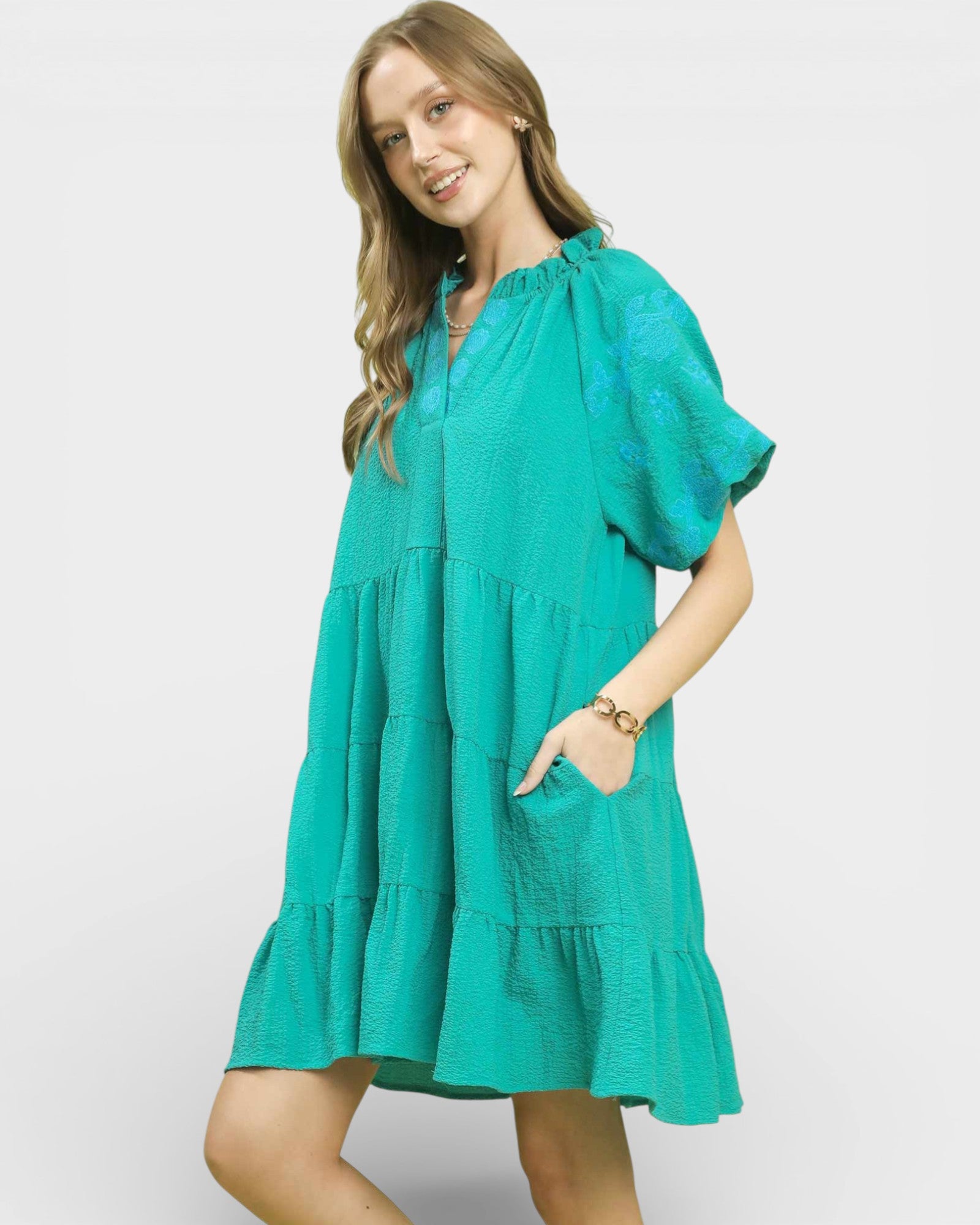 Woman wearing a teal dress on a white background