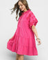 Woman wearing a pink dress with floral patterns on a white background