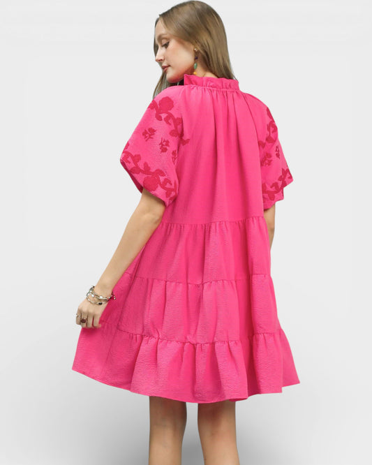 Woman wearing a pink dress with floral patterns on a white background