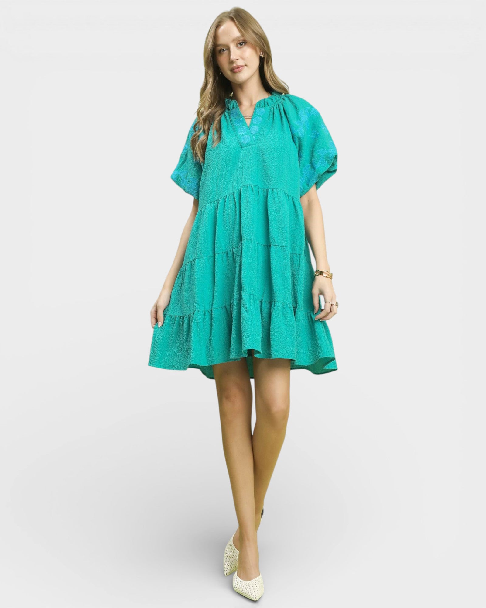 Woman wearing a teal dress on a white background