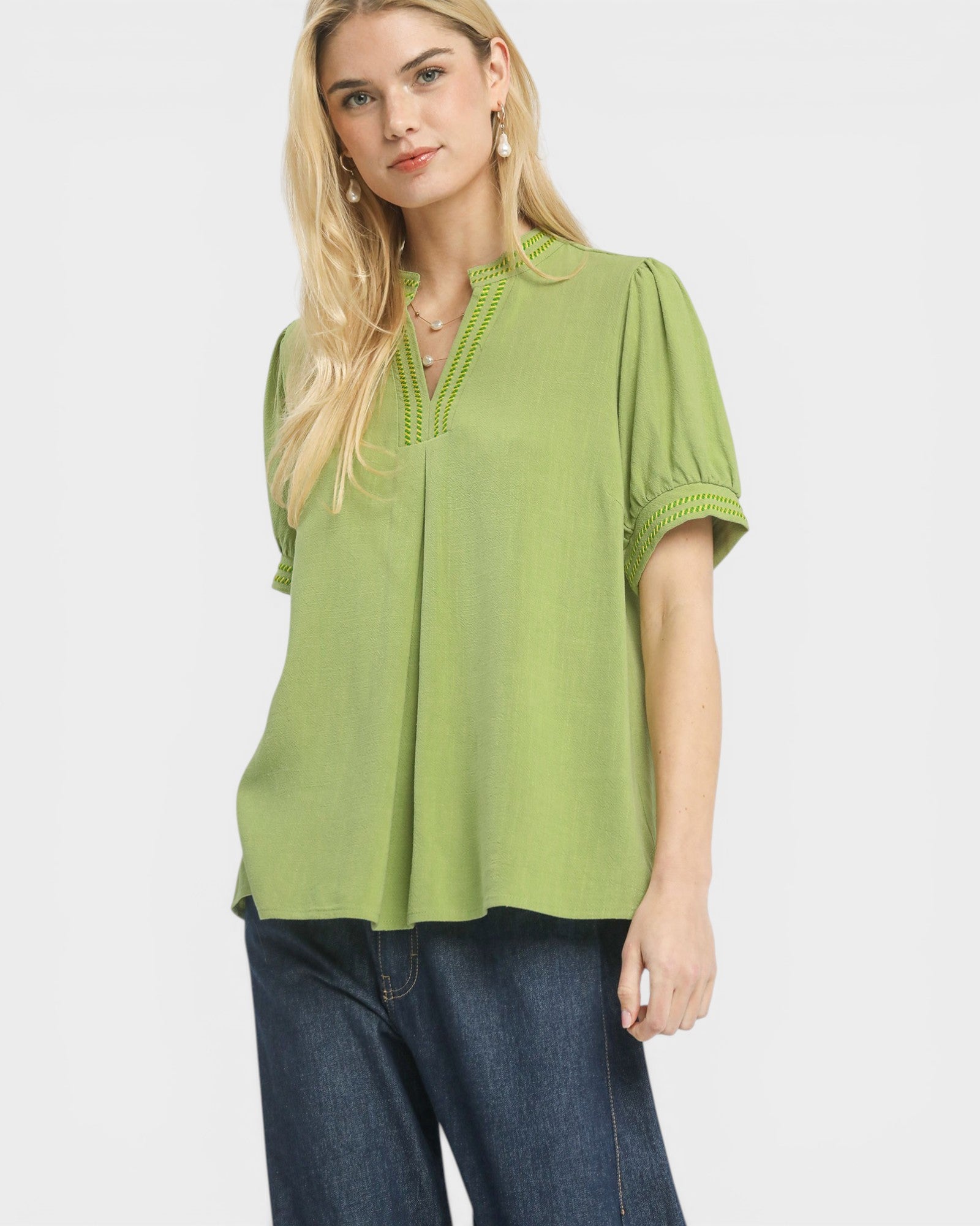 Woman wearing a green blouse with lace details on a white background
