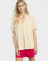 Woman wearing a beige blouse with red accents and pink shorts on a white background