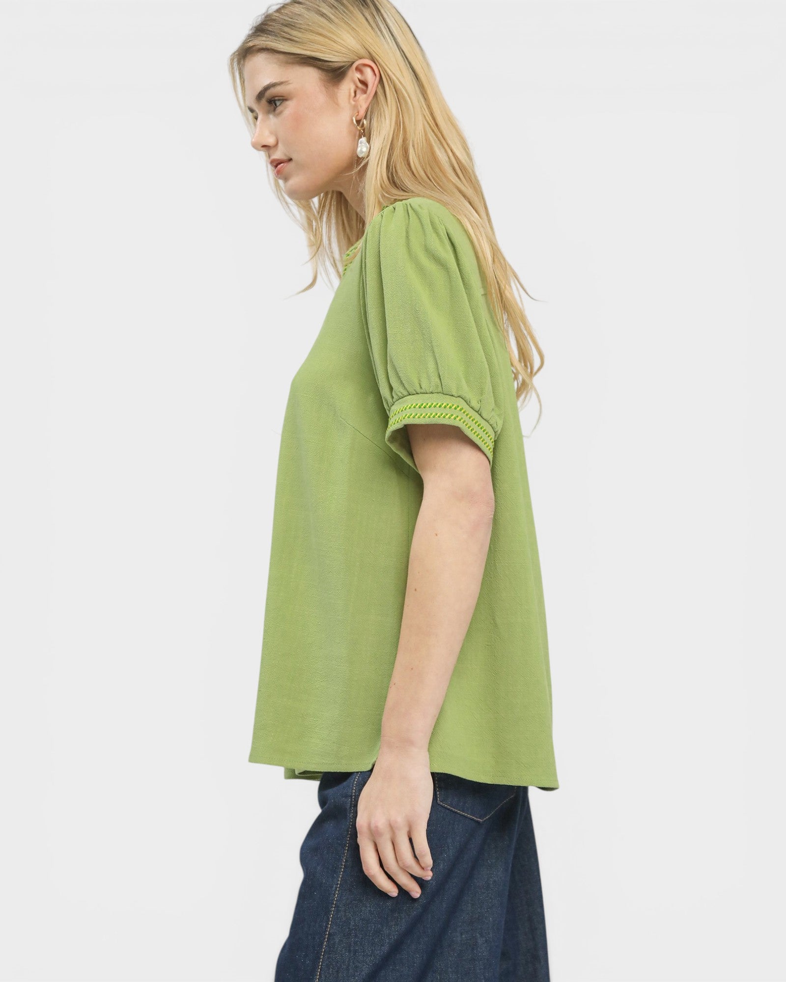 Woman wearing a green blouse with short sleeves on a white background