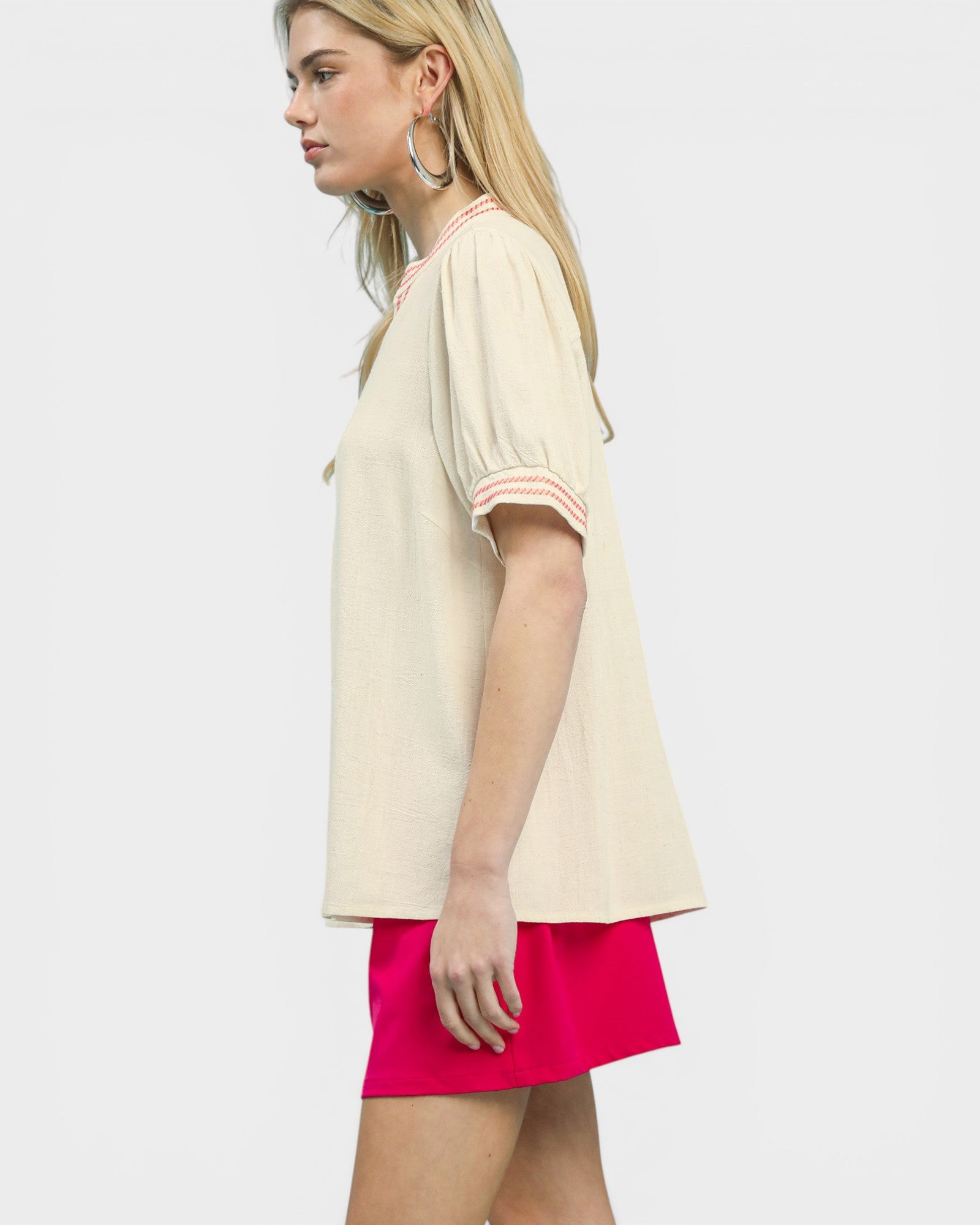 Woman wearing a beige top and pink shorts on a white background