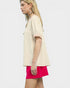 Woman wearing a beige top and pink shorts on a white background