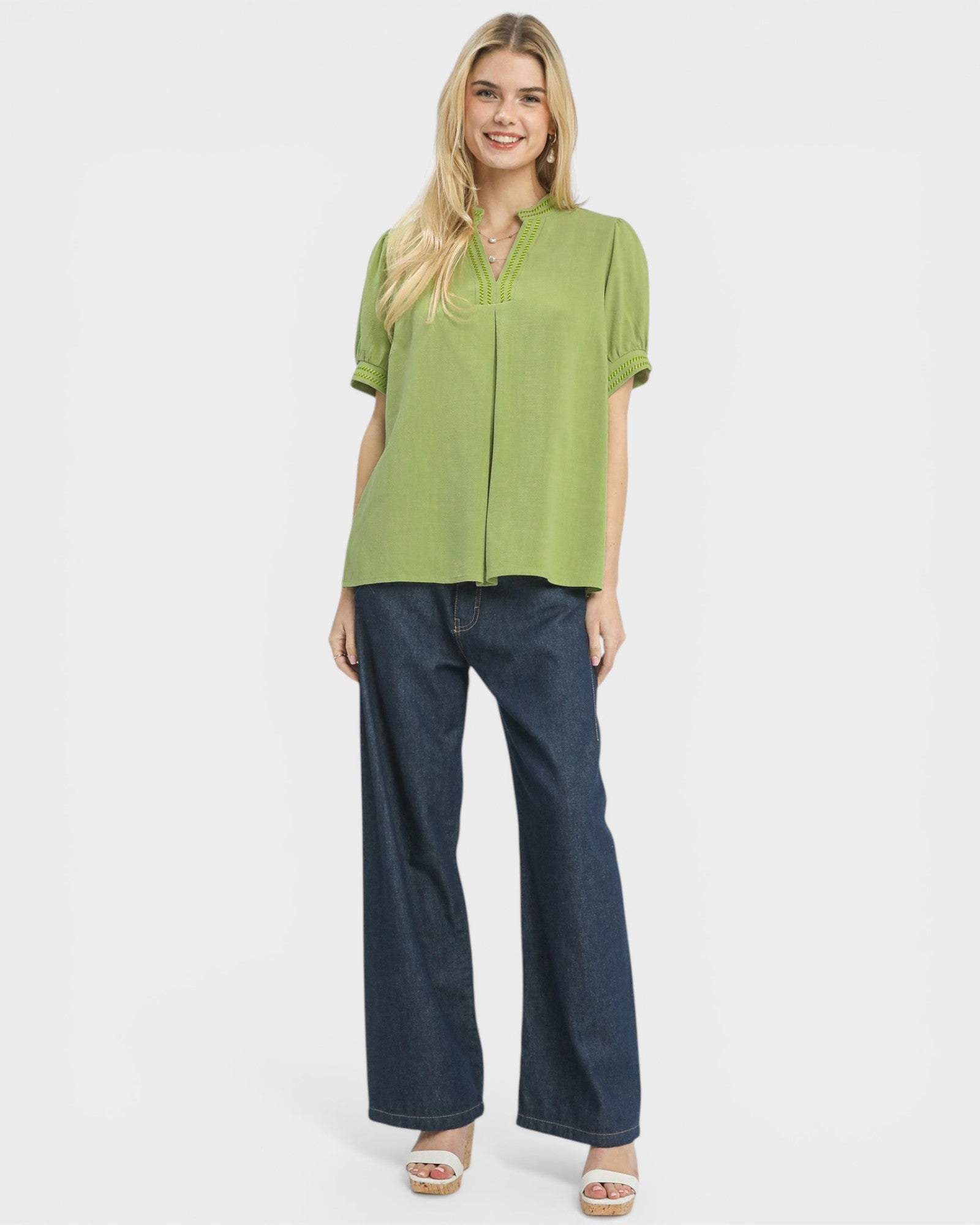 Woman wearing a green blouse and blue jeans on a white background