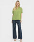 Woman wearing a green blouse and blue jeans on a white background