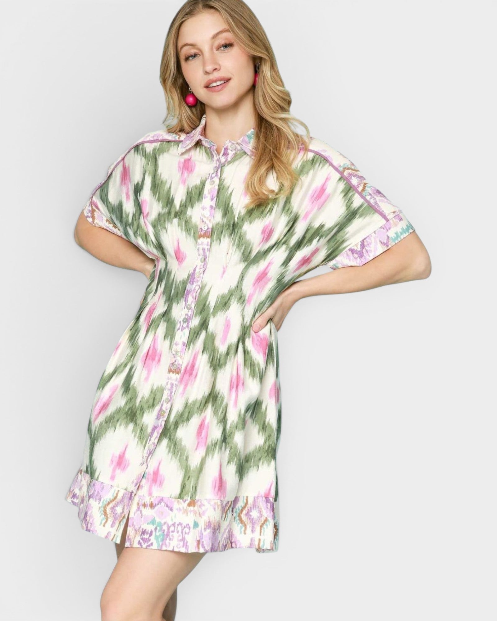 Woman wearing a floral dress with green, pink, and white pattern on a plain background