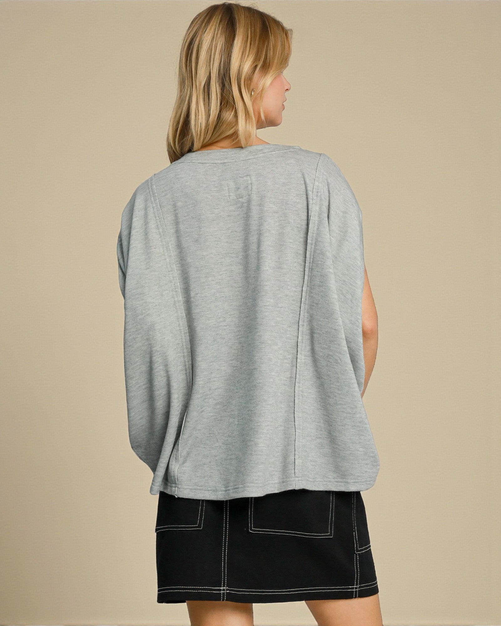 Woman wearing a gray sweater and black skirt on a beige background