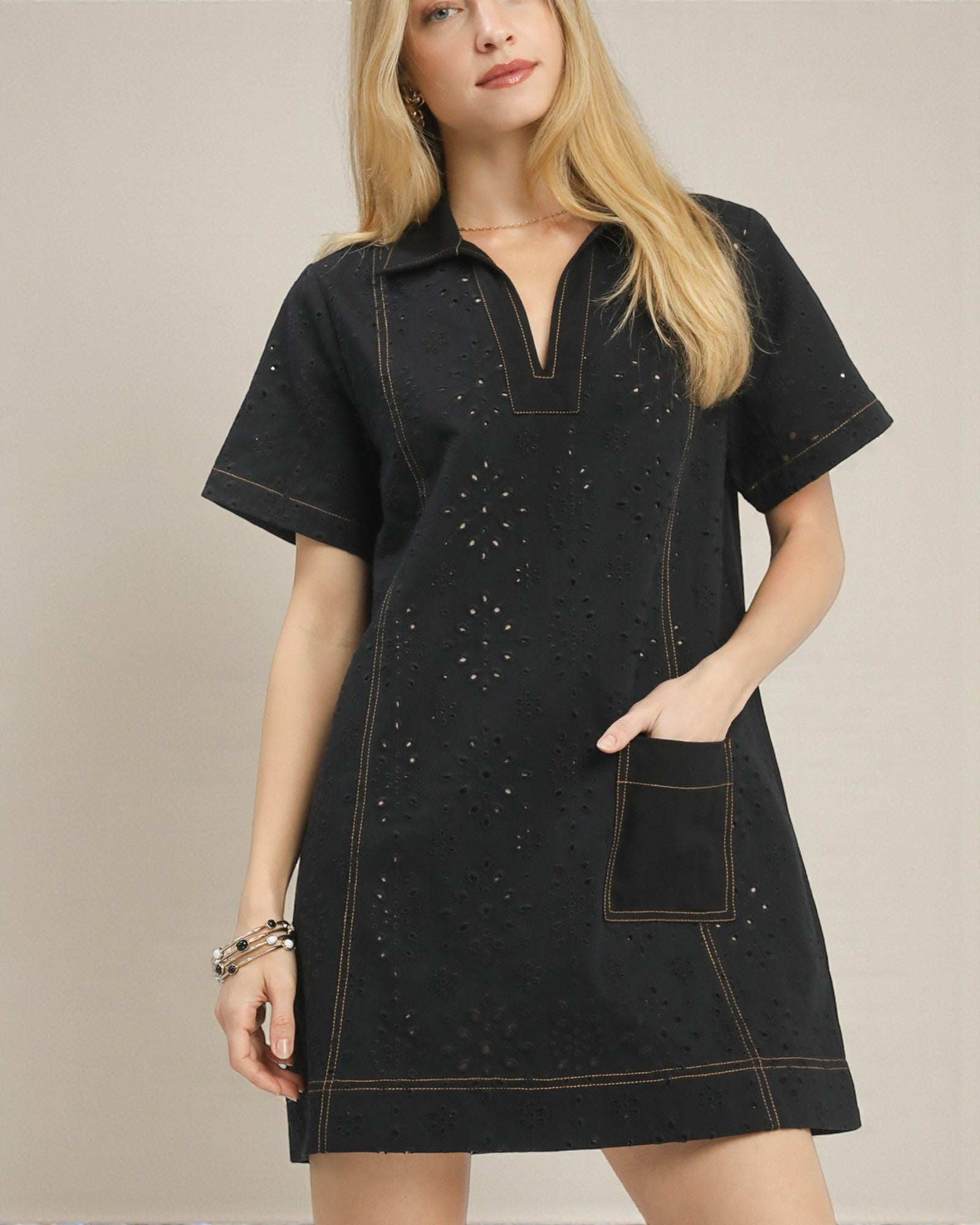 Woman wearing a black dress with decorative stitching on a beige background