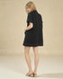 Woman wearing a black dress against a beige background