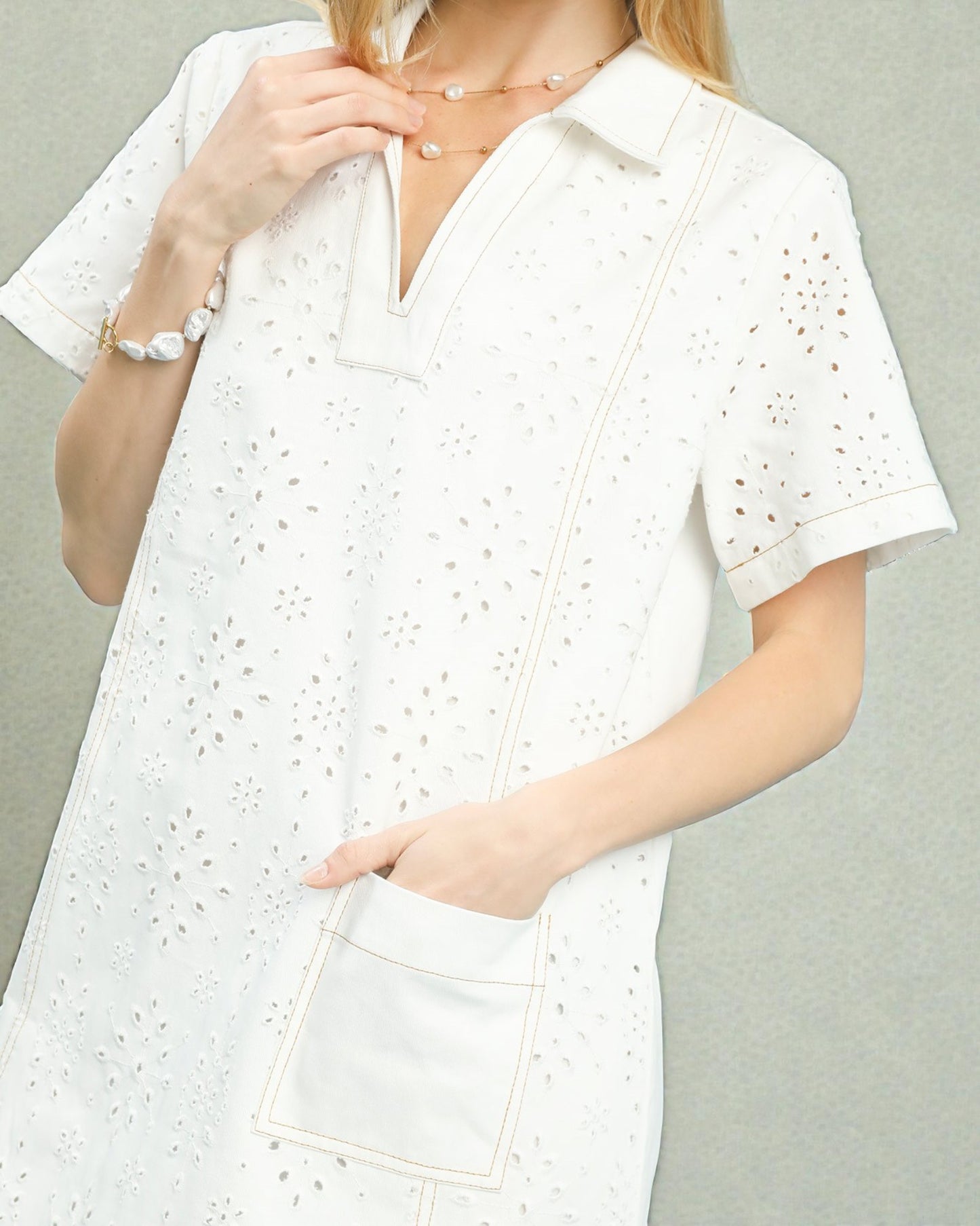 White dress with short sleeves and a collar on a plain background