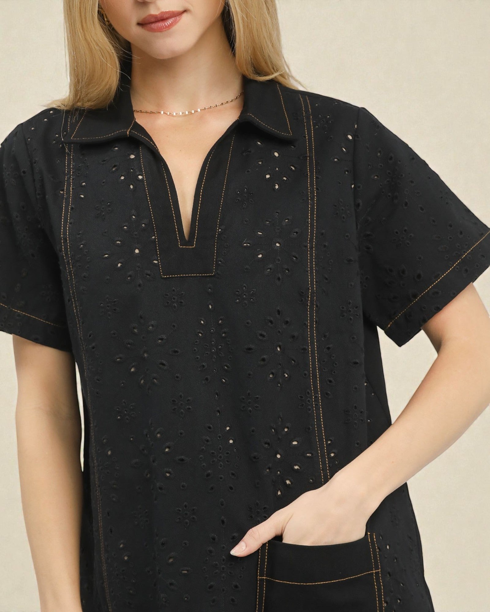 Black dress with intricate detailing worn by a model on a beige background