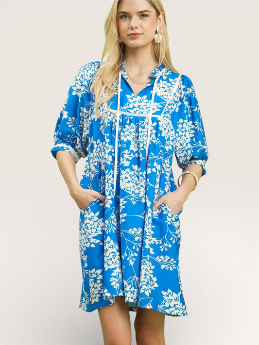 Woman wearing a blue floral dress against a plain background