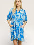 Woman wearing a blue floral dress against a plain background