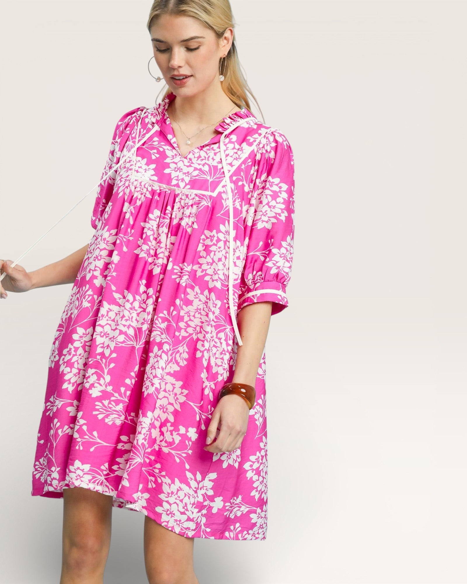 Woman wearing a pink floral dress against a plain background