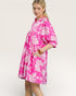 Woman wearing a pink floral dress against a plain background