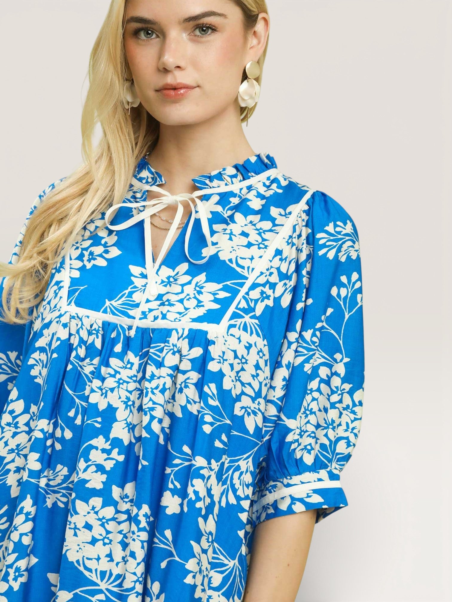 Woman wearing a blue floral dress against a plain background
