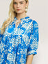 Woman wearing a blue floral dress against a plain background