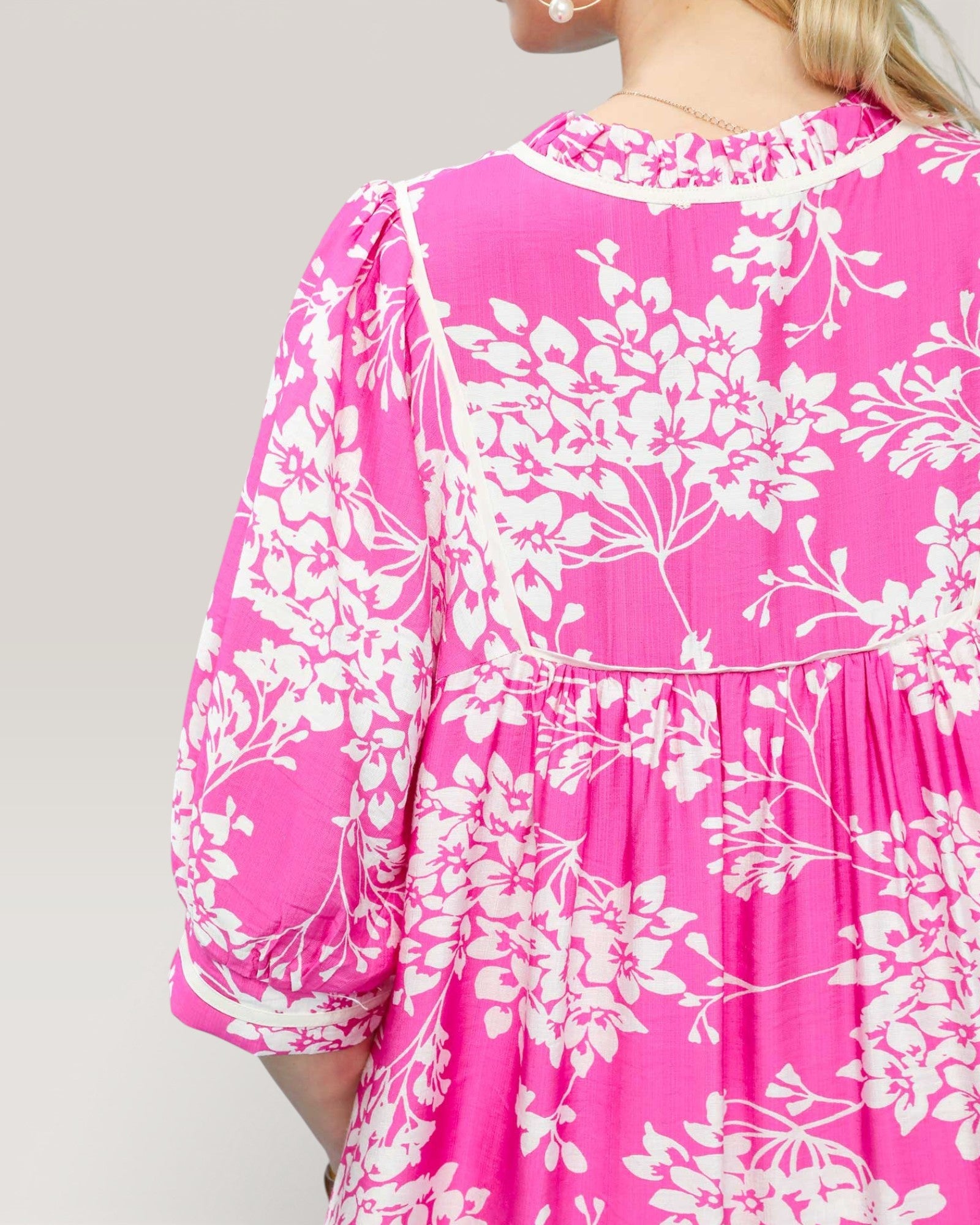 Pink dress with white floral pattern on a plain background