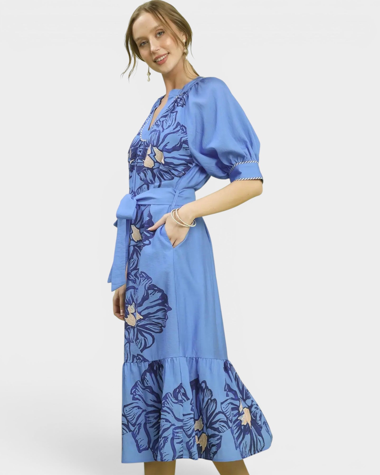Woman wearing a blue dress with floral patterns on a white background