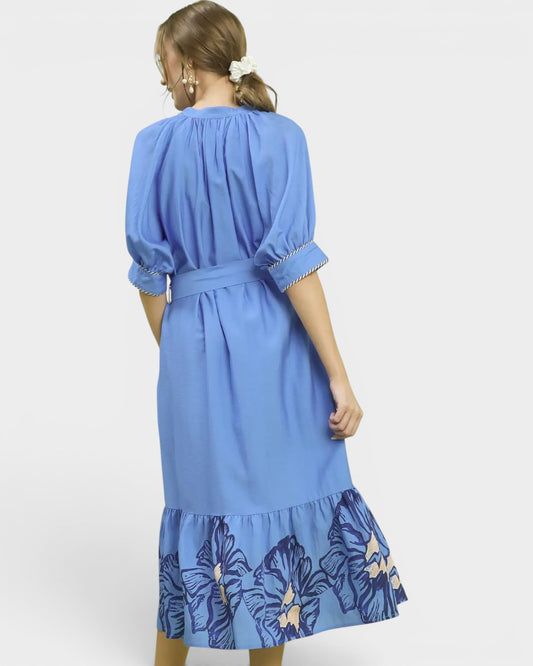 Woman wearing a blue dress with floral hem on a white background