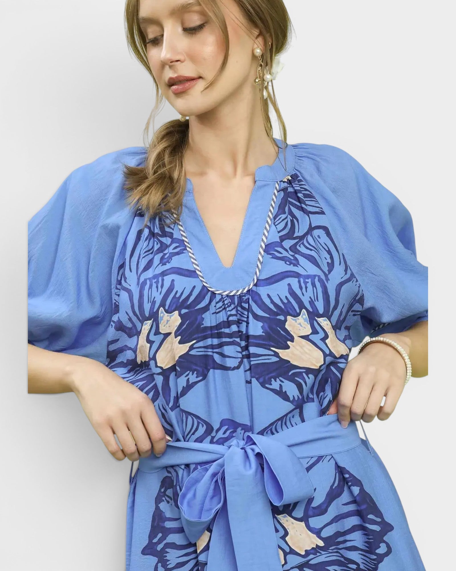 Woman wearing a blue dress with a floral pattern on a white background