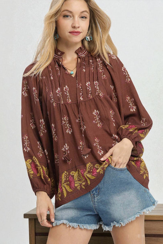 Woman wearing a brown floral blouse and denim shorts on a white background