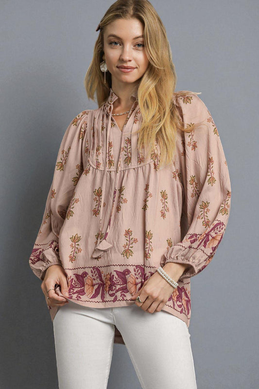 Woman wearing a floral blouse with long sleeves against a gray background