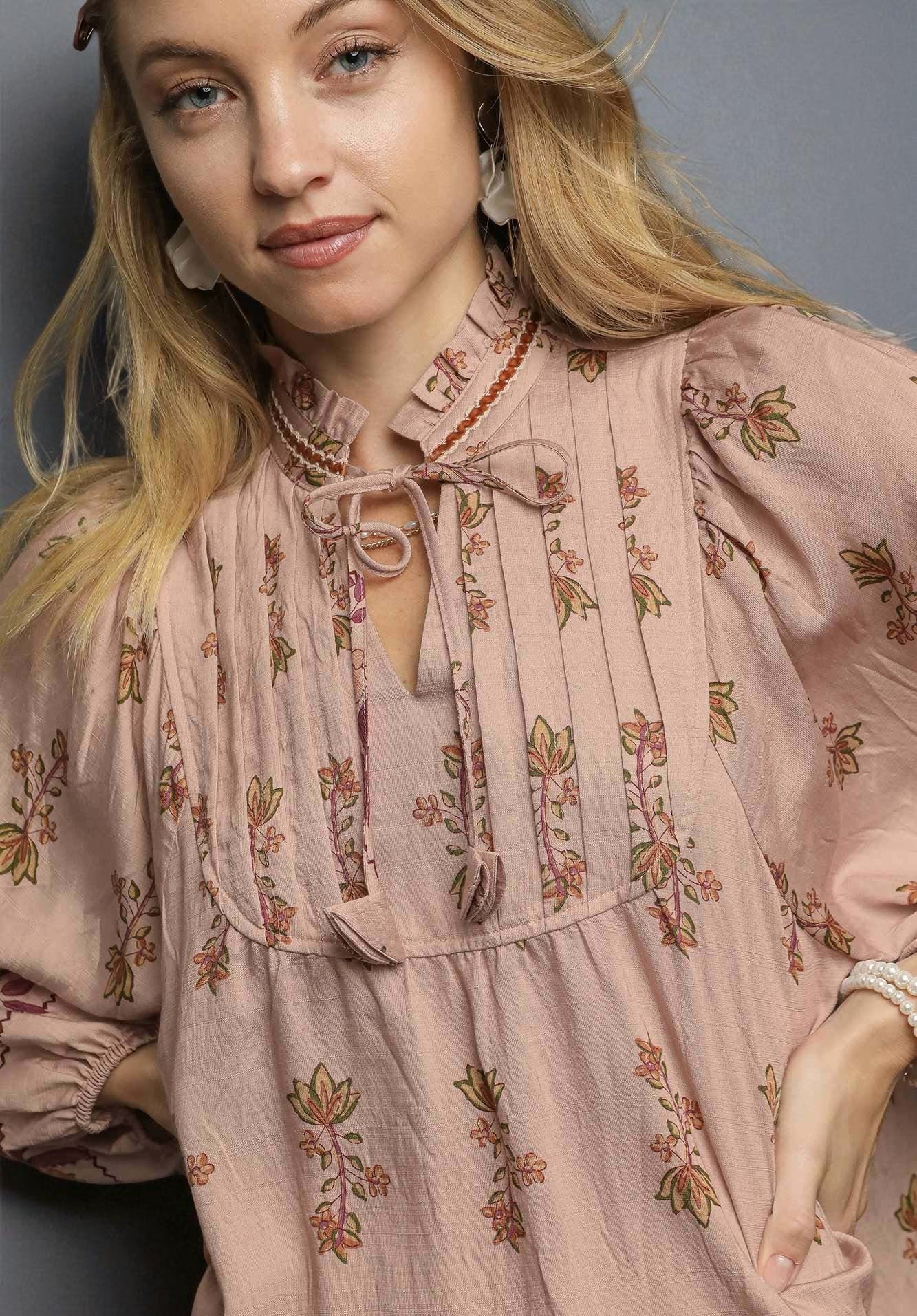 Woman wearing a pink floral blouse against a gray background