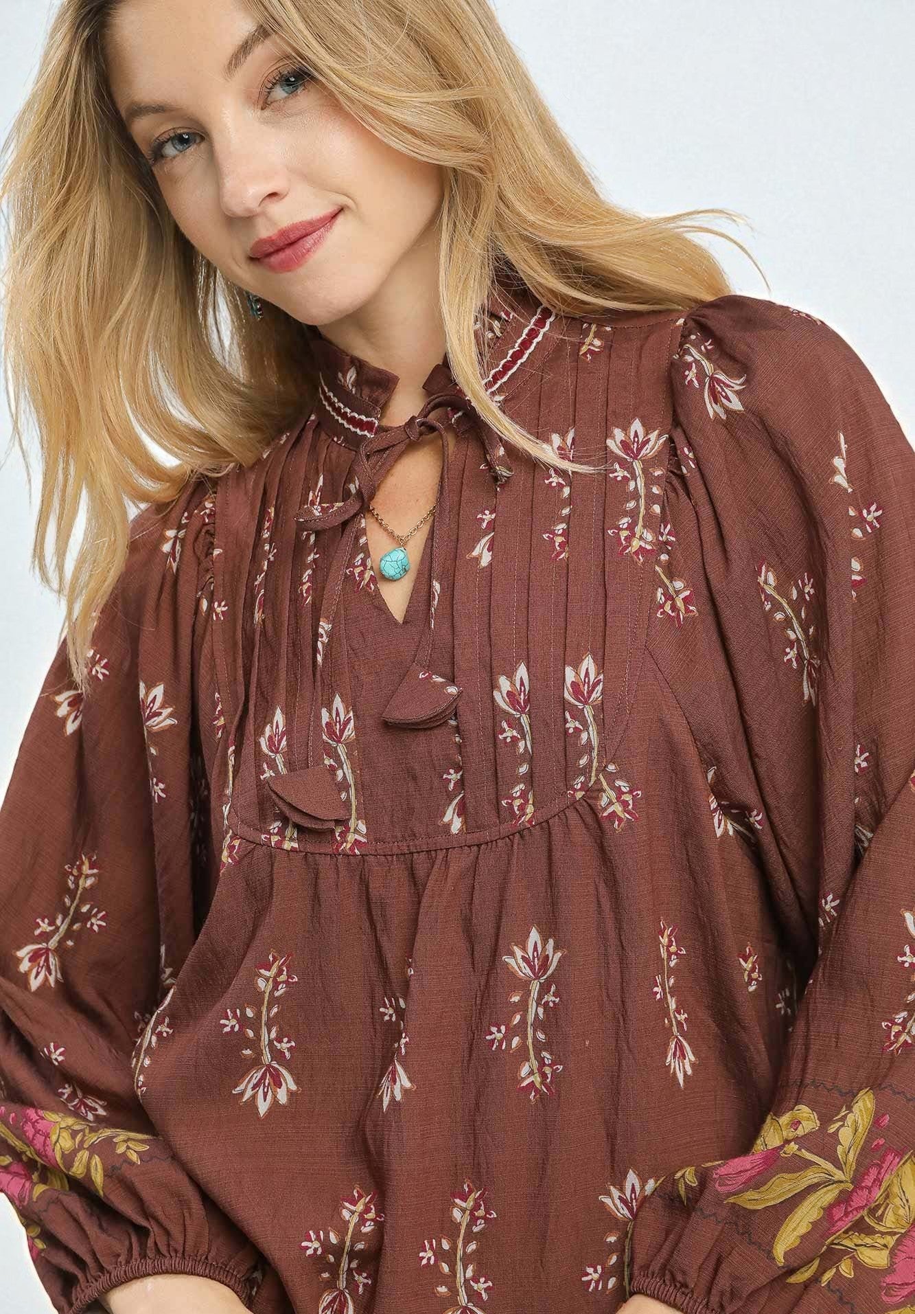 Woman wearing a brown floral blouse with a white background