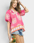 Woman wearing a pink floral blouse with denim shorts against a plain background