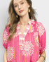 Woman wearing a pink floral blouse with a plain background