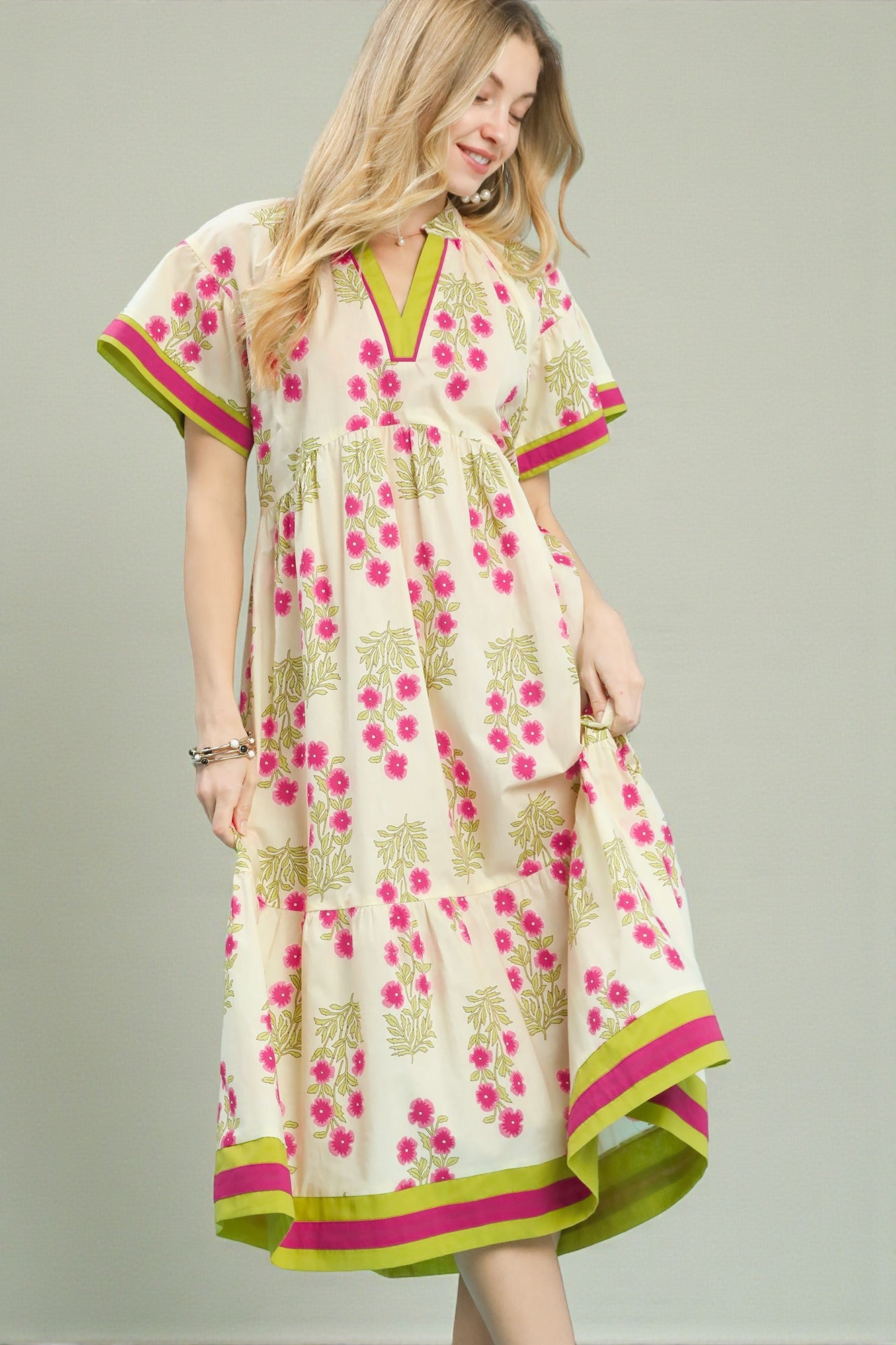 Woman wearing a floral dress with pink and green accents on a gray background