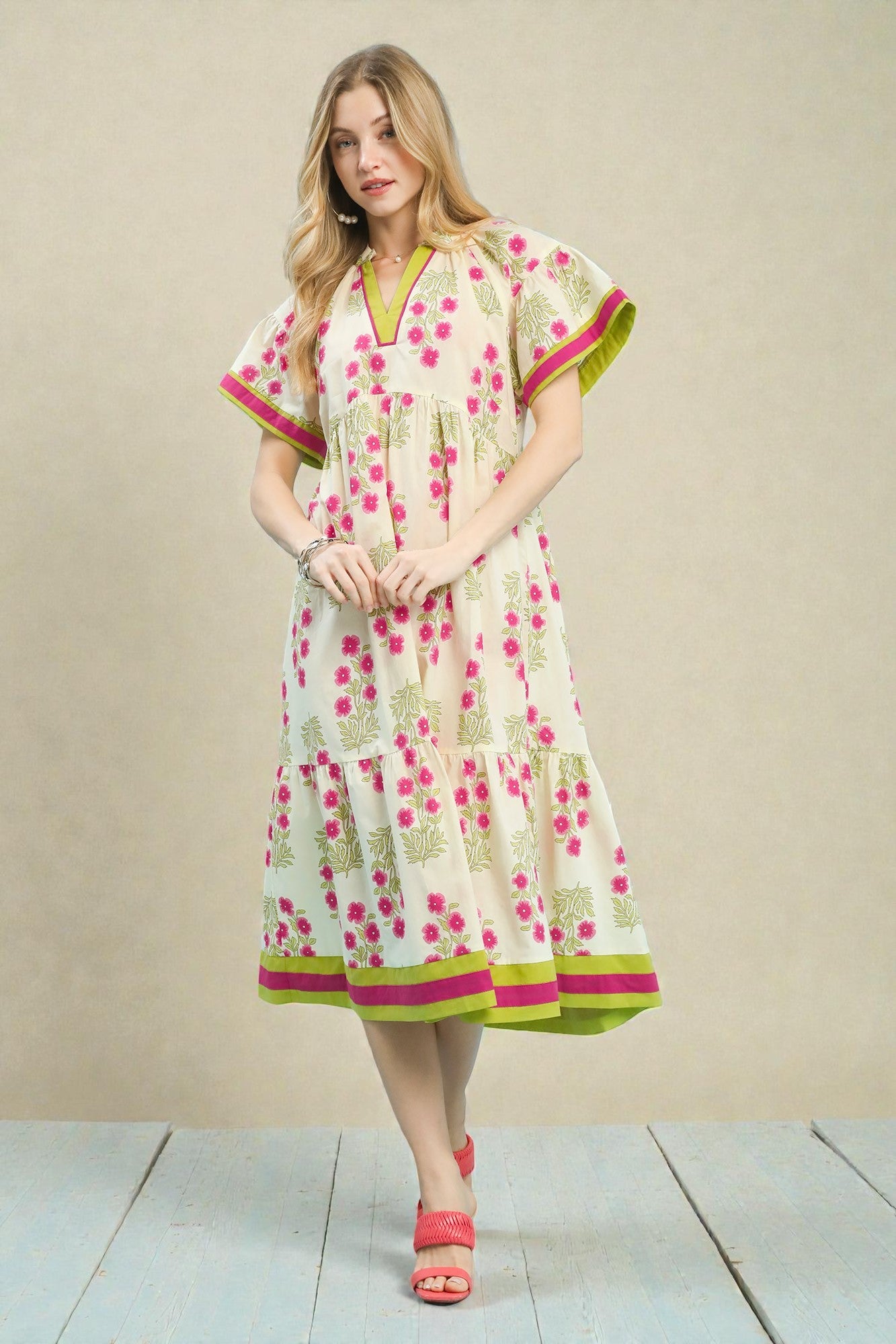 Woman wearing a floral dress with pink and green accents on a beige background