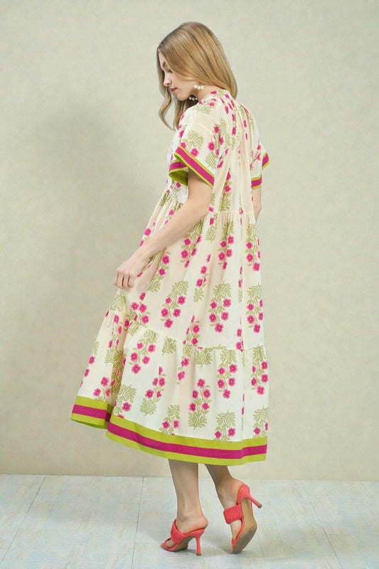 Woman wearing a floral dress with pink and green accents on a plain background