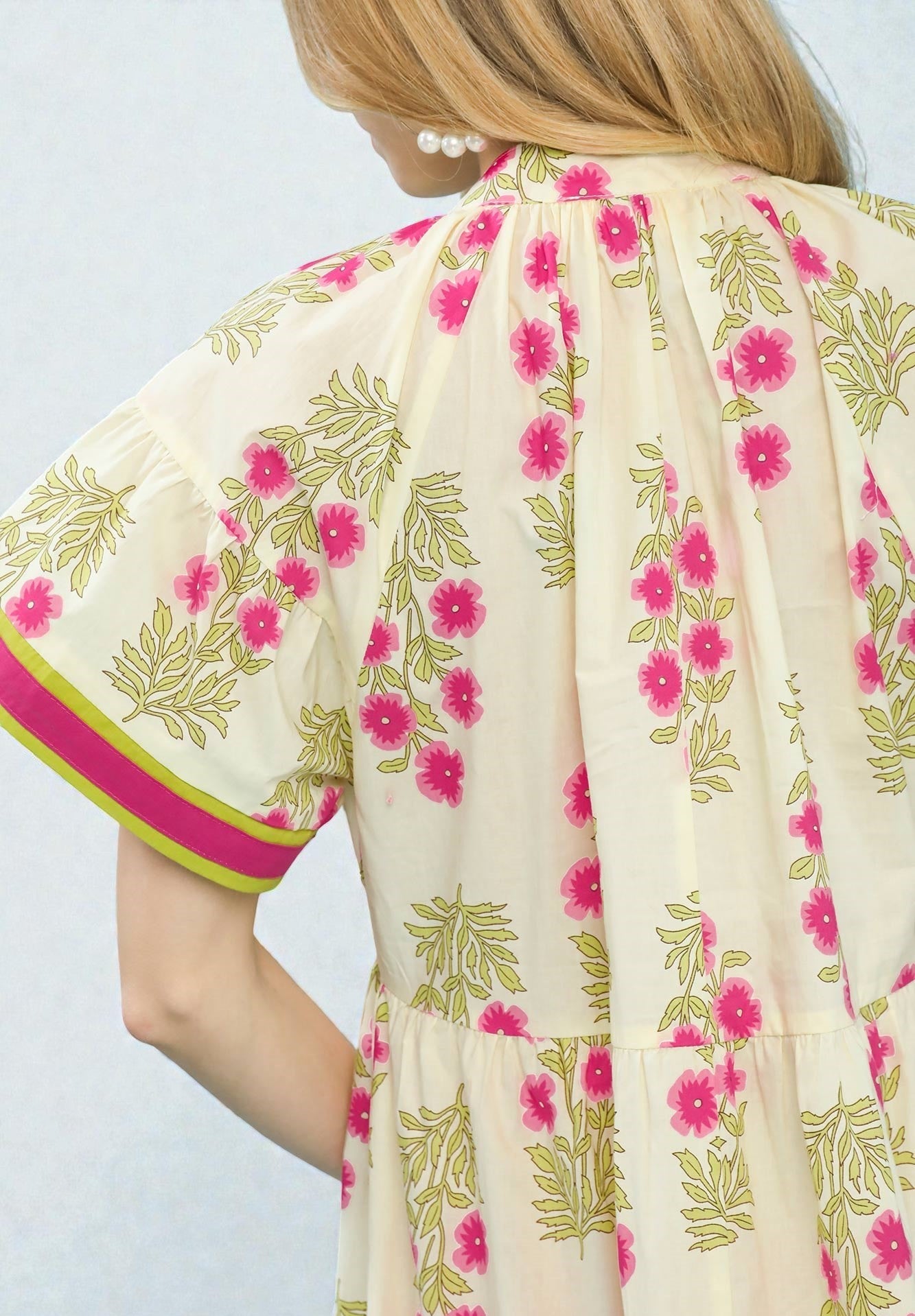 Beige dress with pink floral pattern on a plain background