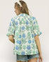 Woman wearing a floral patterned shirt with a plain background