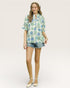 Woman wearing a floral blouse and denim shorts on a white background