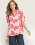 Woman wearing a pink floral blouse with a plain background