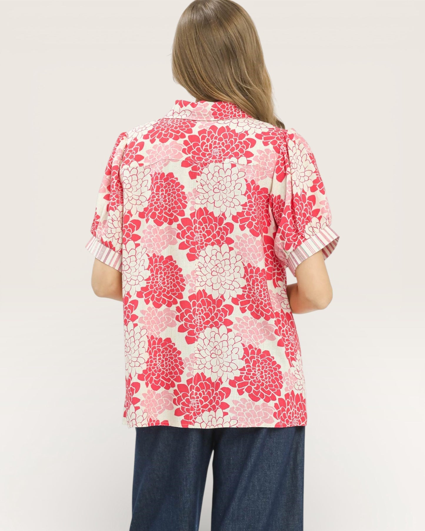 Person wearing a pink floral blouse on a plain background