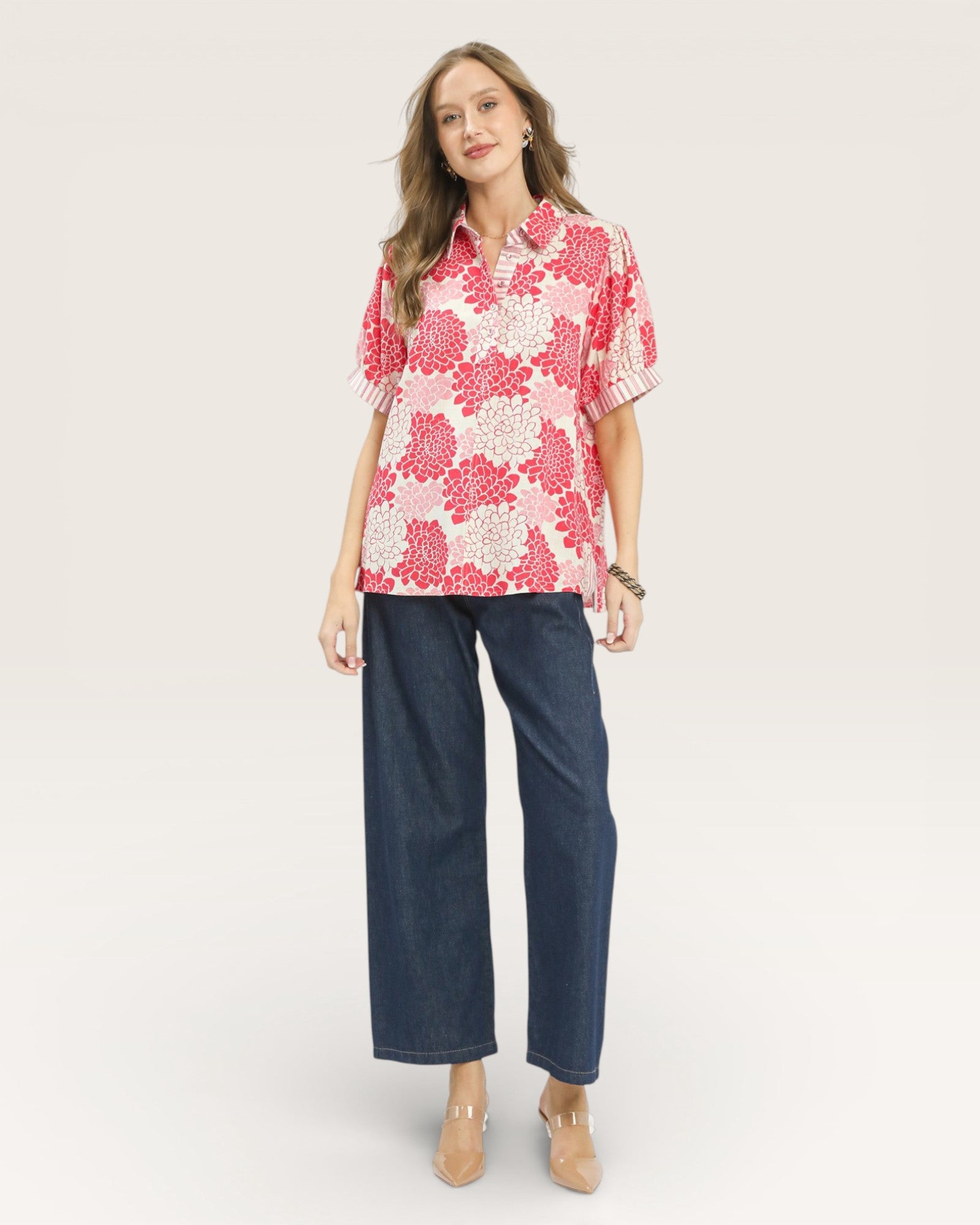Woman wearing a pink floral blouse and blue jeans on a white background