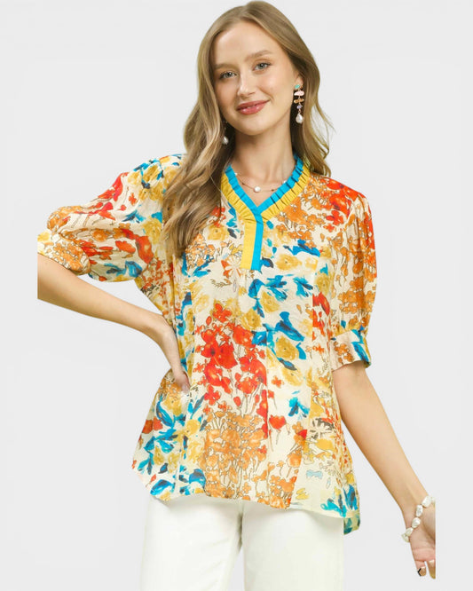 Woman wearing a colorful floral blouse with a plain background
